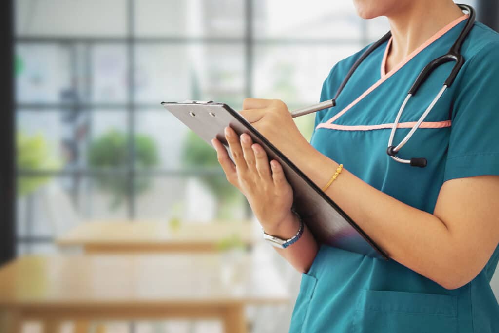 female doctor hold clipboard pad and fill medical history list at workplace.