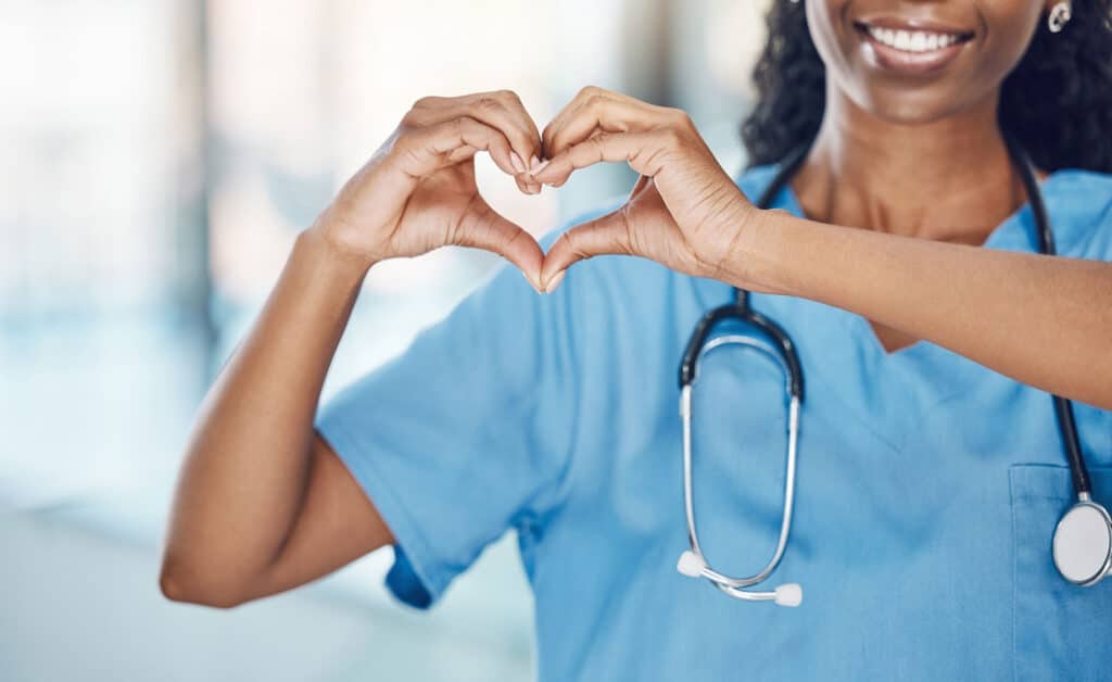 Heart hand and black woman nurse in hospital with expression to show love and care for career. Professional medical facility worker in uniform with happy smile and self love sign at work