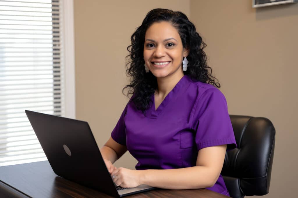 Portrait of a stunning Physical Therapy Assistant with curly black hair, wearing a purple scrubs top